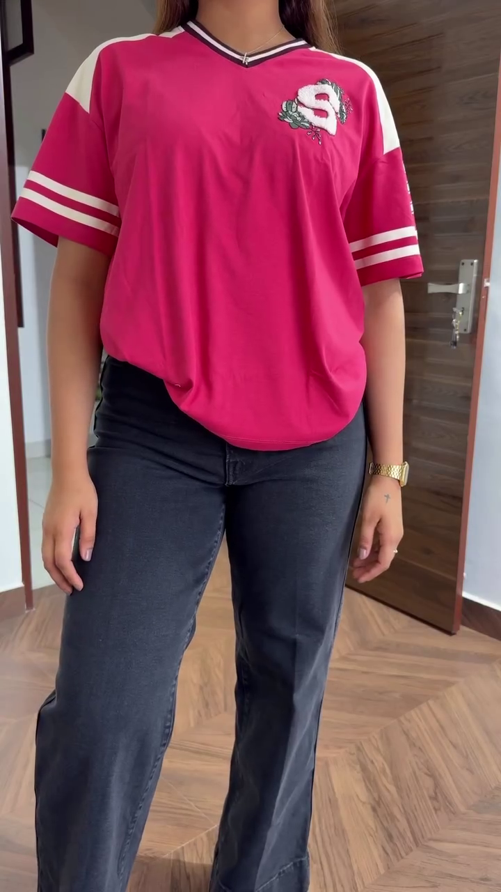 Bright Pink Shirt with White Sleeve Stripes, “S” Emblem, and Number Detailing Paired with Dark Wide-Leg Jeans and Maroon Shoes Casual Sporty Streetwear Look 🌸👕👖👟✨